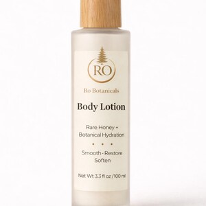 Pu&ograve; includere: Una bottiglia di vetro smerigliato di lozione per il corpo Ro Botanicals con tappo e pompa in legno. L'etichetta include il testo "Rare Honey + Botanical Hydration" e "Smooth, Restore, Soften". La bottiglia contiene 100 ml.