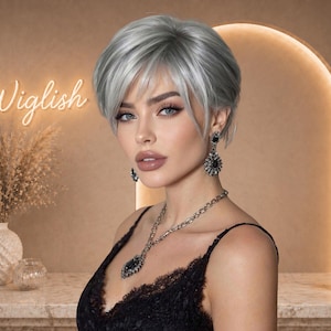 Peut inclure: Une femme aux cheveux courts gris argenté et un haut en dentelle noire. Elle porte un collier et des boucles d'oreilles argentés. Le mot "Wiglish" est écrit en cursive dans une enseigne au néon.