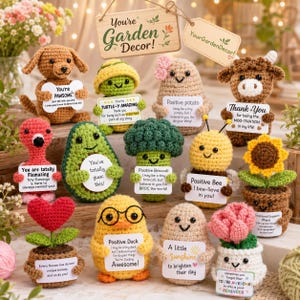 May include: A collection of twelve small crocheted figures, including a dog, turtle, potato, cow, flamingo, avocado, broccoli, bee, sunflower, heart flower, duck, and tulip, each holding a white sign with encouraging text.