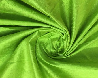 May include: A close-up of a bright green silk fabric, showing the texture and drape of the material.
