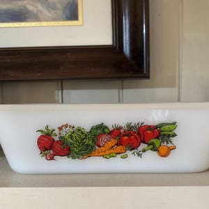 May include: White ceramic baking dish with a colorful illustration of vegetables, including carrots, tomatoes, and green beans.