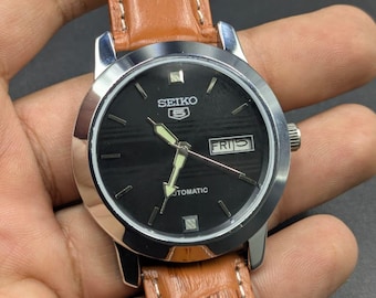 Reloj de pulsera Seiko 5 vintage para hombre con esfera negra, indicador de fecha y día, movimiento automático.