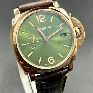 Puede incluir: Un reloj de pulsera Panerai con caja dorada pulida, esfera verde con acabado rayos de sol y correa de cuero marr&oacute;n oscuro. La esfera presenta marcadores de hora dorados, n&uacute;meros ar&aacute;bigos en el 12 y el 6, ventana de fecha en el 3 y segundero en el 9.