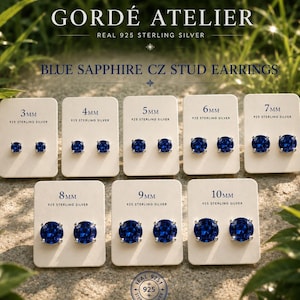 May include: A display of blue sapphire CZ stud earrings in various sizes from 3mm to 10mm, set in 925 sterling silver. The earrings are presented on individual cards, with the brand name "GORDÉ ATELIER" at the top.