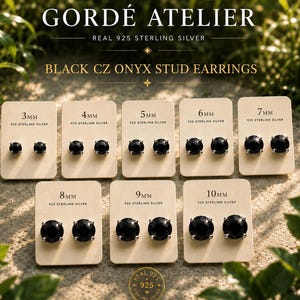 Puede incluir: Pendientes de botón de ónix negro CZ en varios tamaños, de 3 mm a 10 mm, exhibidos en tarjetas individuales. Las tarjetas están etiquetadas con el tamaño y "925 Sterling Silver". La marca "Gordé Atelier" está en la parte superior.