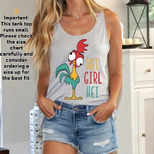 Puede incluir: Una camiseta sin mangas gris claro con un dise&ntilde;o de gallo de dibujos animados y las palabras "HEI GIRL HEI" en colores brillantes. La camiseta sin mangas se combina con pantalones cortos de mezclilla. El texto en el lado izquierdo de la imagen dice: "Importante: Esta camiseta sin mangas es peque&ntilde;a."