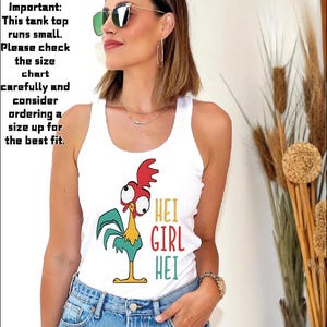 Puede incluir: Camiseta sin mangas blanca con un gr&aacute;fico de gallo de dibujos animados y el texto "HEI GIRL HEI" en rojo, amarillo y verde. La camiseta sin mangas se usa con jeans azules. La imagen tambi&eacute;n incluye texto que dice que la camiseta sin mangas es peque&ntilde;a.