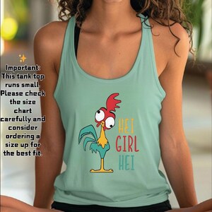 Puede incluir: Una camiseta sin mangas de color verde azulado claro con un gr&aacute;fico de gallo de dibujos animados y las palabras "HEI GIRL HEI" en amarillo, rojo y turquesa. La camiseta sin mangas tiene cuello redondo y es sin mangas. El texto a la izquierda de la imagen dice "Important: This tank top runs small."