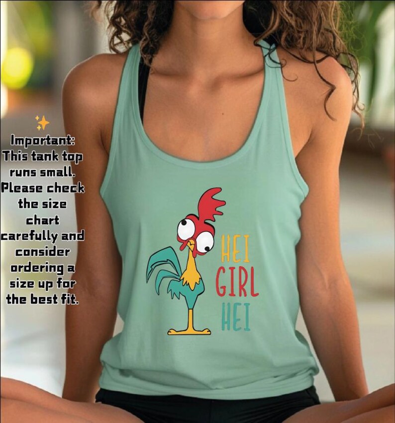 Puede incluir: Una camiseta sin mangas de color verde azulado claro con un gr&aacute;fico de gallo de dibujos animados y las palabras "HEI GIRL HEI" en amarillo, rojo y turquesa. La camiseta sin mangas tiene cuello redondo y es sin mangas. El texto a la izquierda de la imagen dice "Important: This tank top runs small."
