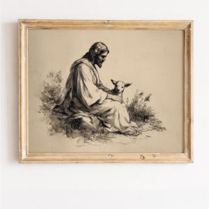 Könnte beinhalten: Ein gerahmter Sepia-Druck zeigt eine Figur mit langen Haaren und Bart, die sitzt und ein Lamm hält. Das Kunstwerk ist im Vintage-Stil gehalten, mit einem hellen Hintergrund und einem goldfarbenen Holzrahmen. Das Bild weckt ein Gefühl von Frieden und Gelassenheit.