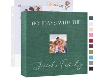 May include: A green photo album with a linen texture. The front cover has a window with a family photo inside. The text "HOLIDAYS WITH THE Jericho Family" is printed on the front cover.