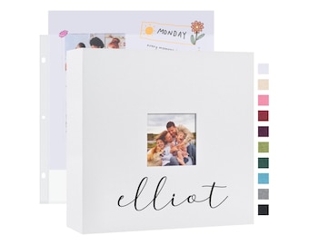 May include: White photo album with a window for a photo. The photo shows a family of four in a field. The album has the name "elliot" written on the front in black cursive.