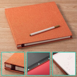 K&ouml;nnte beinhalten: Ein orangefarbenes, mit Stoff bezogenes Hardcover-Journal mit einem wei&szlig;en Stift darauf. Das Journal hat einen roten R&uuml;cken und ein schwarzes Lesezeichenband. Das Journal ist auf einer leeren Seite mit Wassertropfen ge&ouml;ffnet.