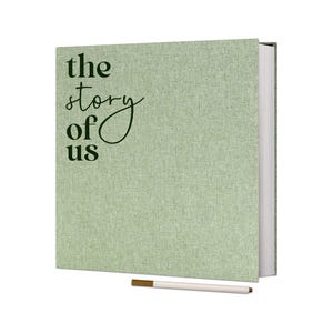 May include: A green linen-covered journal with the text "the story of us" in black lettering. A white pen with a gold tip is included.