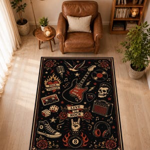 May include: A rectangular area rug featuring a black background with a rock and roll theme. The design includes a red electric guitar, a skull, a microphone, a cassette tape, dice, headphones, an amplifier, a sneaker, and an eight ball. Text reads "LIVE TO ROCK", "ROCK FOREVER", and "PLAY LOUD".