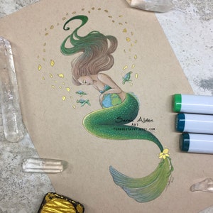 May include: A green mermaid with long flowing hair cradles a globe in her arms. She is surrounded by small sea turtles and a trail of golden sparkles. The artwork is signed "Sarah Alden Art" and includes the website "foreverfairy.etsy.com".
