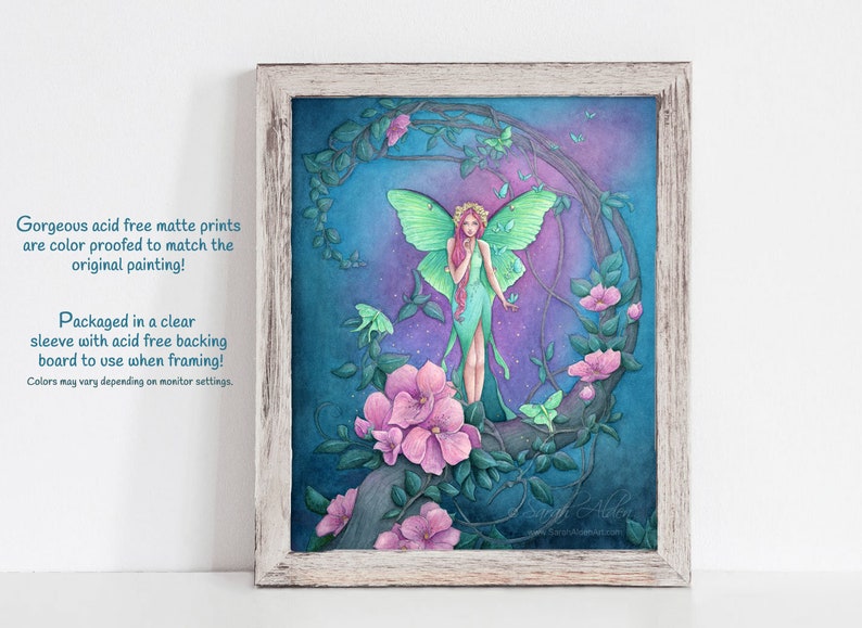 May include: A framed print of a watercolor painting featuring a fairy with green wings and a long green dress standing on a branch with pink flowers. The background is a dark blue with a crescent moon shape and green leaves. The print is surrounded by a white wooden frame.