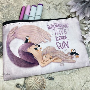 May include: A white zippered pouch with a purple mermaid and the text "Mermaids Have More Fun". The mermaid is surrounded by three small black and white birds.