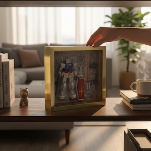 May include: A framed, three-dimensional model of a Gundam robot, featuring red, blue, yellow, and white accents. The model is displayed within a gold-colored frame, showcasing detailed mechanical components and a shield. The artwork is set on a wooden shelf.