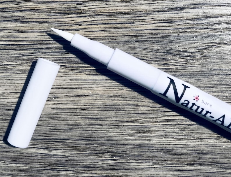 A white marker with the word "Naturals" written on it, lying on a wooden surface.