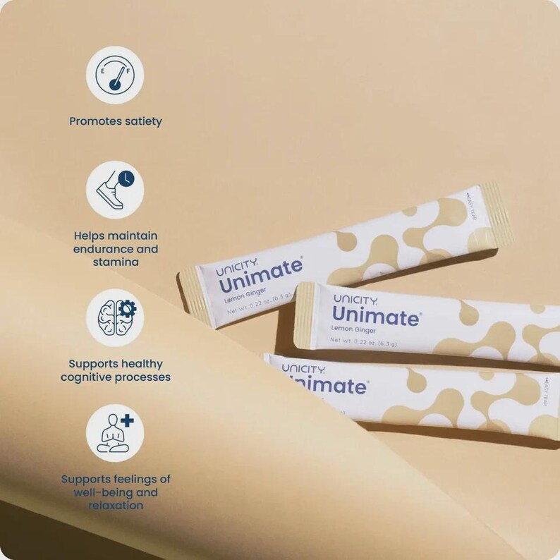 May include: Three white and beige Unicity Unimate Lemon Ginger packets are displayed on a light brown surface. The packets have a pattern of beige organic shapes. Text on the packets includes "Unimate" and "Lemon Ginger."