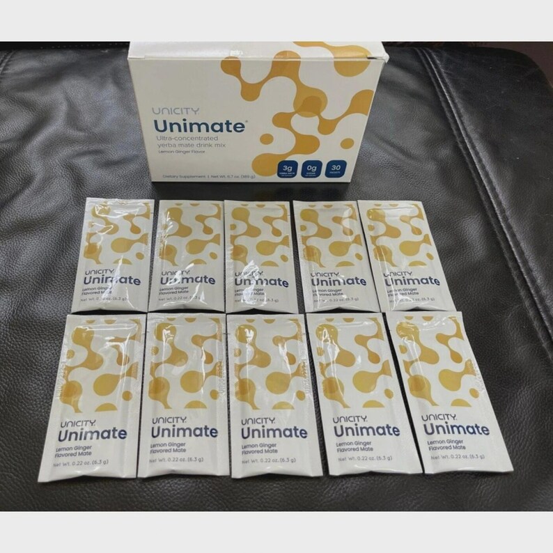 May include: A box and individual packets of Unicity Unimate drink mix. The box is white with a yellow abstract design and the Unicity logo. The packets are white with yellow patterns and the words "Unimate" and "Lemon Ginger Flavoured Mate".