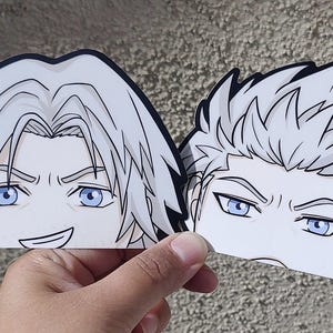 May include: Two anime-style stickers featuring male characters with white hair and blue eyes. One sticker shows a smiling face, the other a stern expression. The stickers are held by a hand.