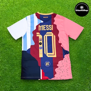 Può includere: Una maglia da calcio a maniche corte con un design multicolore caratterizzato da strisce bianche e azzurre, un pannello centrale blu scuro e bordeaux e una sezione rosa. Il retro mostra il nome MESSI e il numero 10 in oro con loghi di squadra.