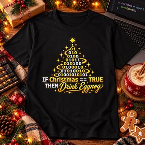 Könnte beinhalten: Ein schwarzes Kurzarm-T-Shirt mit einer Grafik eines Weihnachtsbaums, der aus Binärcode-Ziffern besteht. Unter dem Baum steht der Text: IF Christmas == TRUE THEN Drink Eggnog. Das Design verwendet gelbe und weiße Farben.