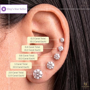 May include: Five round, clear, faceted stud earrings arranged vertically on an earlobe. Labels indicate carat weights: 0.2 Carat Total (0.1 Carat Each), 0.4 Carat Total (0.2 Carat Each), 0.6 Carat Total (0.3 Carat Each), 1 Carat Total (0.5 Carat Each), and 2.0 Carat Total (1.0 Carat Each).
