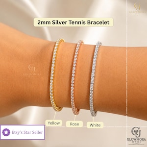 May include: Three 2mm tennis bracelets in yellow, rose, and white metal finishes, each featuring a continuous row of small, clear, round-cut stones. The text 2mm Silver Tennis Bracelet is displayed at the top, with labels for Yellow, Rose, and White.