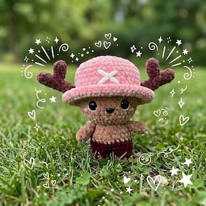 May include: A handmade crochet plush toy of a cartoon character, with a pink hat and white cross, brown antlers, and a brown and maroon outfit. The toy is set in grass with white doodles.