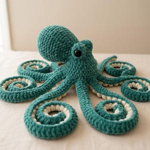 May include: A teal crocheted octopus plush toy with white accents on the tentacles. The octopus has a round head, large black eyes, and eight curled tentacles. The plush is made of soft, textured yarn.