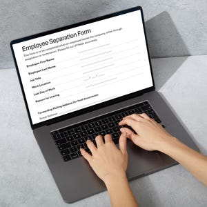 May include: A laptop displaying an "Employee Separation Form" on its screen. The form includes fields for employee information and is being filled out. The laptop is open, and hands are typing on the keyboard.