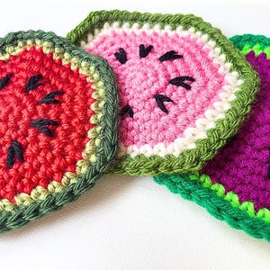May include: Three handmade crochet coasters in the shape of watermelon slices. The coasters feature red, pink, and purple centers with black seed details, and green and light green edging. These decorative coasters are perfect for a summer theme.