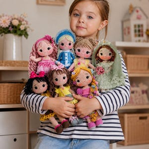 May include: A young girl holds a collection of handmade crochet dolls. Each doll has unique features, including different hairstyles, dresses, and accessories. The dolls are in various colors, including pink, blue, yellow, and green. The girl is wearing a striped shirt and jeans.