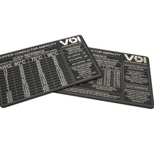 May include: Two black rectangular reference cards featuring white printed text and tables titled Copper Conductor Ampacity. The cards display technical data, including AWG sizes, temperature ratings, and overcurrent limitations for electrical wiring.