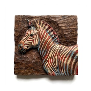 Op de afbeelding: Een handgesneden houten wandkunstwerk met een zebrahoofd in profiel. De strepen van de zebra zijn geschilderd in rood, wit en blauw, afstekend tegen de donkerbruine houten achtergrond. Het kunstwerk is vierkant en heeft een getextureerd oppervlak.
