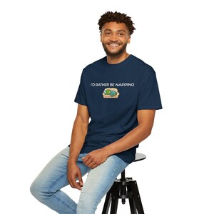 Pode incluir: Camiseta azul marinho com o texto "I'D RATHER BE NAPPING" acima de um gráfico de uma tartaruga em um sofá. A camisa é feita de um material macio.