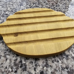 Puede incluir: Un jabonera de madera con forma de limón. La madera de color claro presenta ranuras horizontales para el drenaje. Los bordes son redondeados y el diseño es sencillo y funcional. Mide unos 15 cm de largo.