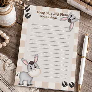 May include: A rectangular notepad featuring a beige and white striped border, a cartoon donkey at the bottom left, a donkey head at the top right, and the text "Long Ears, Big Plans Write it down" at the top center above horizontal lined paper.