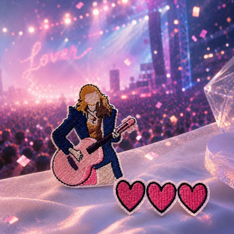 May include: An embroidered patch featuring a figure with long blonde hair wearing a dark blue jacket and playing a pink acoustic guitar, accompanied by three smaller heart-shaped embroidered patches with pink centers and black borders.