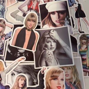 May include: A collection of die-cut stickers featuring various photographic portraits of Taylor Swift in different outfits, hairstyles, and poses, including one black and white image with the word Lover written on the arm and a butterfly tattoo.