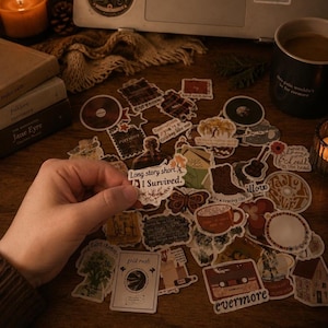 Pode incluir: Uma cole&ccedil;&atilde;o de autocolantes decorativos com v&aacute;rios desenhos, incluindo uma borboleta, uma ch&aacute;vena de caf&eacute; e uma cassete. Os autocolantes t&ecirc;m uma est&eacute;tica vintage e o texto "Long story short, I Survived." &eacute; vis&iacute;vel.