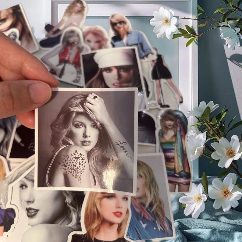 May include: A square sticker featuring a black and white portrait of a person with long hair, a butterfly tattoo on the shoulder, and the word Lover written in cursive on the forearm. The sticker is held against a collection of similar stickers.