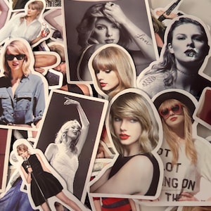 May include: A collection of die-cut stickers featuring various photographic portraits and performance images of Taylor Swift. The stickers display diverse outfits, hairstyles, and poses, including one with the text Lover and another with text reading NOT NOT ING ON THE.