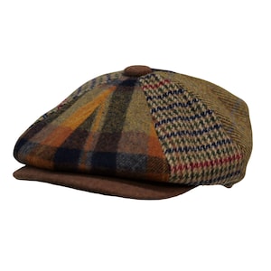 Peut inclure: Casquette de style gavroche marron avec un design patchwork. La casquette présente une visière marron et un bouton sur le dessus. Le patchwork comprend des motifs à carreaux et en chevrons dans des tons marron, orange et bleu.