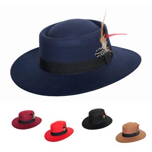 May include: A navy blue fedora hat with a black band and feather detail. The hat features a wide brim and a rounded crown. Additional hats in red, black, and brown are shown.