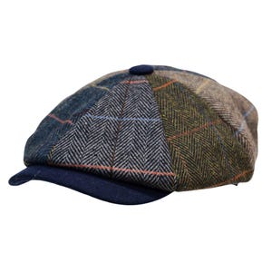 May include: A multi-colored patchwork flat cap featuring a variety of tweed fabric panels with herringbone patterns in shades of blue, gray, olive green, and brown, accented by thin orange and blue windowpane checks and a solid navy blue brim.