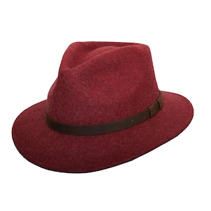 May include: A burgundy fedora hat with a dark brown leather band. The hat has a classic teardrop crown and a wide brim. The hat is made of a soft, felt-like material.